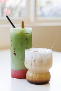 Chilled iced matcha latte and iced coffee on a white table, perfect for a refreshing break.
